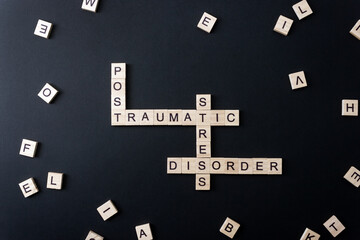 Words Post Traumatic Stress Disorder on wooden blocks on black background. Minimal concept PTSD