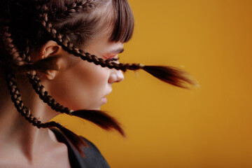 Portrait of a young woman model with braids, rear view. Braids fly from the turn of the head on a...