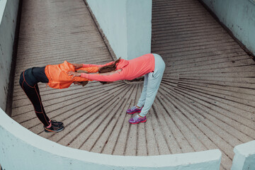 Two women warming up together and preparing for a morning run in an urban environment. Selective focus 