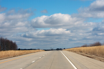 An empty interstate with a blue sky and white clouds. 