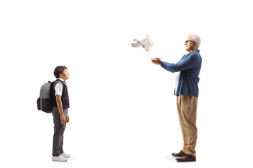 Full length profile shot of a schoolboy watching a man letting a white dove fly