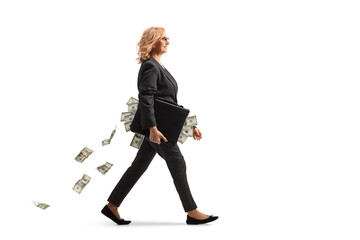 Full length profile shot of a businesswoman walking and carrying a briefcase full of money