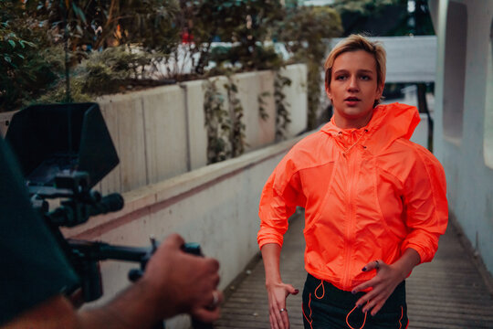 A professional cameraman with equipment and a stabilizer recoding woman for a commercial advertisement as they run in an urban environment
