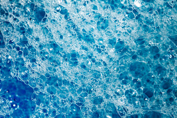 Foam on surface of liquid blue detergent, big and small bubbles, close-up full depth of field, top view