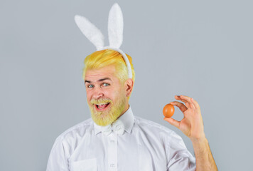 Eggs hunt. Smiling man in rabbit ears with Easter egg. Bearded man in bunny ears. Easter rabbit man...