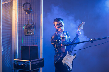 Punk rocker blowing air kisses and acting flirty, playing guitar and having heavy metal style in...