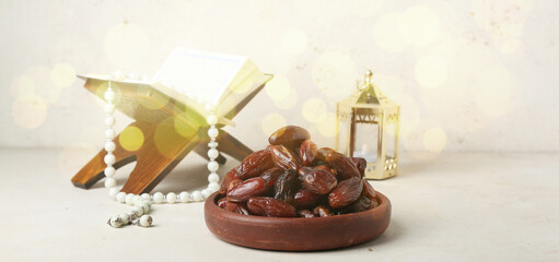 Tasty dates, Quran book and Muslim lantern on light background
