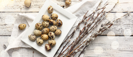 Plate with Easter quail eggs and pussy willow branches on light wooden background
