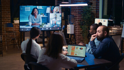 Remote team discussing analytics report in business meeting videocall, diverse employees talking in videoconference at night time. Office workers chatting in teleconference, brainstorming