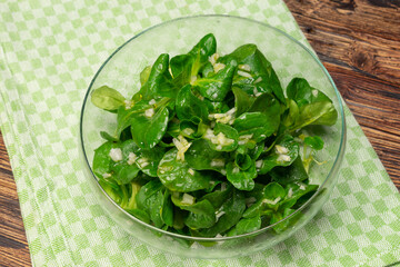 Vogerl Acker Salat mit Dressing auf grünem Tuch Holz forografiert 