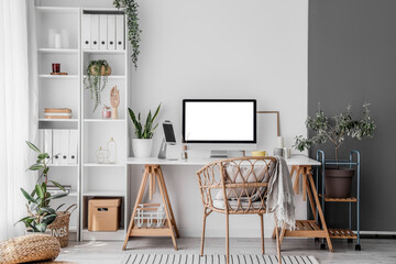 Interior of light office with workplace, shelving unit and houseplants
