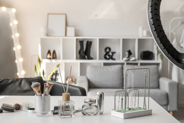 Table with jewelry, brushes, cosmetics and reed diffuser in makeup room