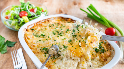 Käsespätzle mit Salat auf einem Holzbrett 