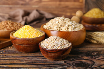 Bowls with different cereals on wooden background