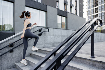 Smiling sporty woman running up stairs during morning exercising outside.