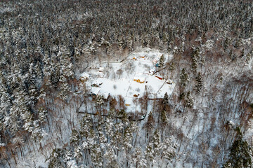 A small holiday village in the middle of a coniferous winter forest, aerial view