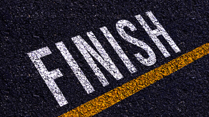 Obraz premium Finish text written and yellow line on the road in middle of the asphalt road, for business planning strategies and challenges, road to success concept, Finish word on street