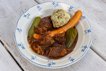Gulasch mit Rindfleisch, Würstchen, Semmelknödel und Gurken 