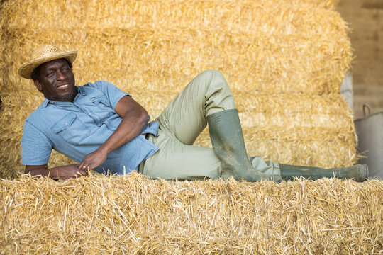 Portrait of smiling man farm worker posing at haystack
