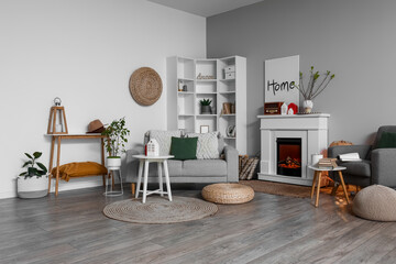 Interior of light living room with fireplace, tables and house candle holders