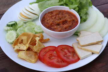 Homemade Muslim salad with sweet sauce on wood table background. Green salad halal food on white plate. 