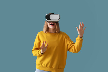 Pretty young woman in VR glasses on blue background