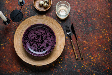Beautiful table setting with stylish plates, glass of water and quail eggs on brown grunge background