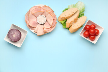 Plate and bowls with ingredients for ham sandwich on blue background