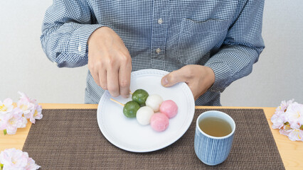三色団子と桜｜和菓子を食べる男性