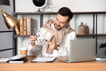 Male tutor with molecular model giving online Physics lesson at home
