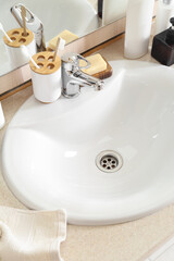Fototapeta premium Ceramic sink and bath supplies on table, closeup
