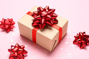 Gift box with red bows and stars on pink background, closeup