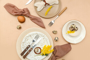 Fototapeta na wymiar Stylish table setting with Easter eggs and mimosa flowers on color background