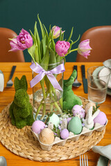 Festive table setting with tulip flowers, painted eggs and bunnies for Easter celebration