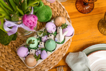Festive table setting with tulip flowers, painted eggs and bunnies for Easter celebration