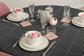 Festive table setting with painted eggs and gypsophila flowers served for Easter celebration