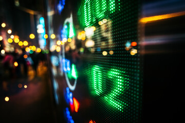 Fototapeta na wymiar Financial stock exchange market display screen board on the street with and city light reflections, selective focus