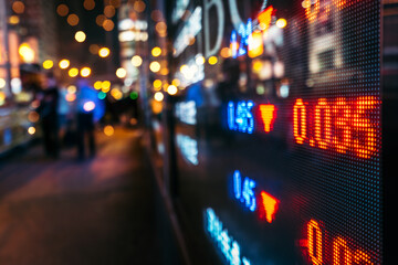 Financial stock exchange market display screen board on the street with and city light reflections, selective focus