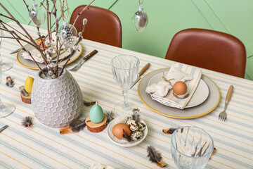Festive table setting with eggs, pussy willow branches and feathers served for Easter celebration