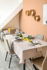 Interior of dining room with table served for Easter celebration near beige wall