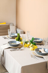 Interior of dining room with table served for Easter celebration near beige wall