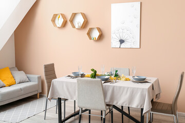 Interior of dining room with table served for Easter celebration near beige wall