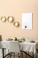 Interior of dining room with table served for Easter celebration near beige wall