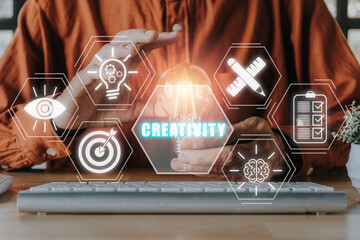 Creativity concept, Person hand holding light bulb on desk with Creativity icon on virtual screen.