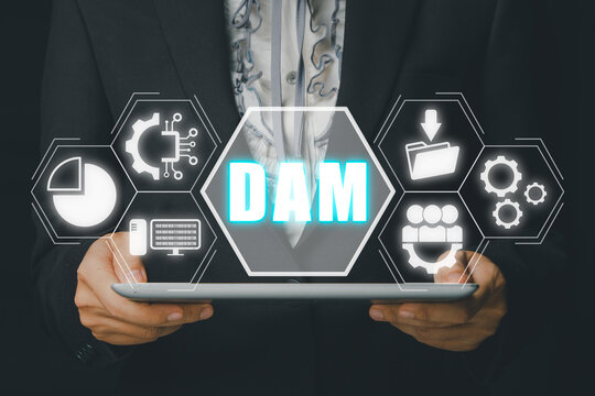 DAM, Digital Asset Management Organization Concept, Person hand using digital tablet with Digital Asset Management icon on virtual screen.
