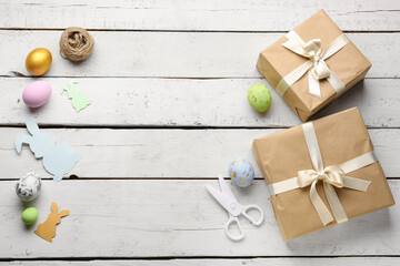 Frame made of gifts, Easter eggs, scissors and rope on white wooden background
