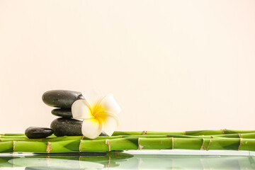 Stack of spa stones, bamboo and flower on light background