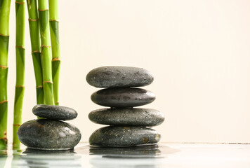 Fototapeta na wymiar Stack of spa stones and bamboo in water on light background