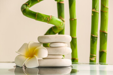 Stack of spa stones, flower and bamboo on light background