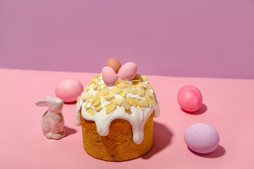 Easter cake, painted eggs and bunny on pink background